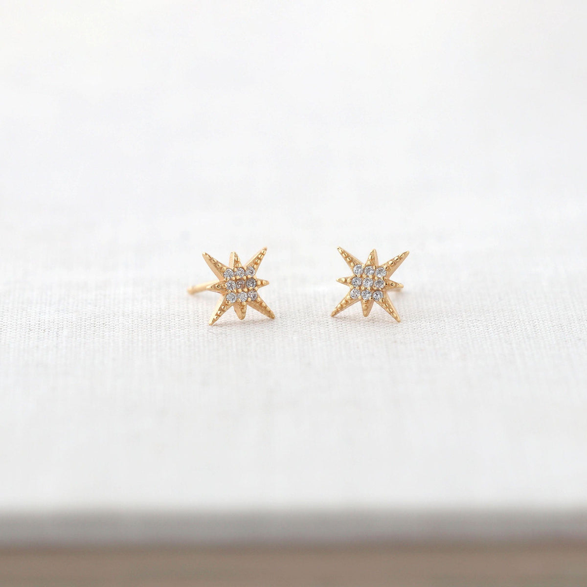 Starburst Crystal Stud Earrings in 18K gold vermeil on a white book