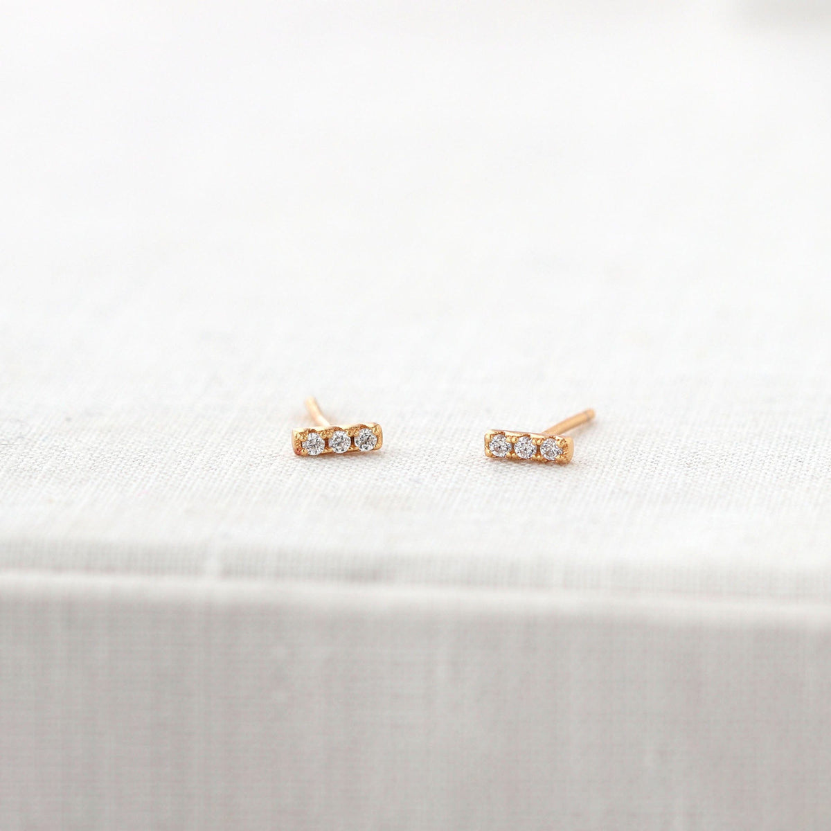 Bar Dash Crystal Stud Earrings in 18K gold vermeil on a white book
