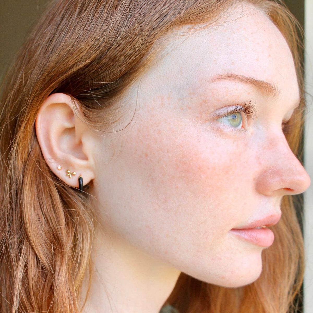 Woman with red hair wearing an Enamel Huggie Hoop