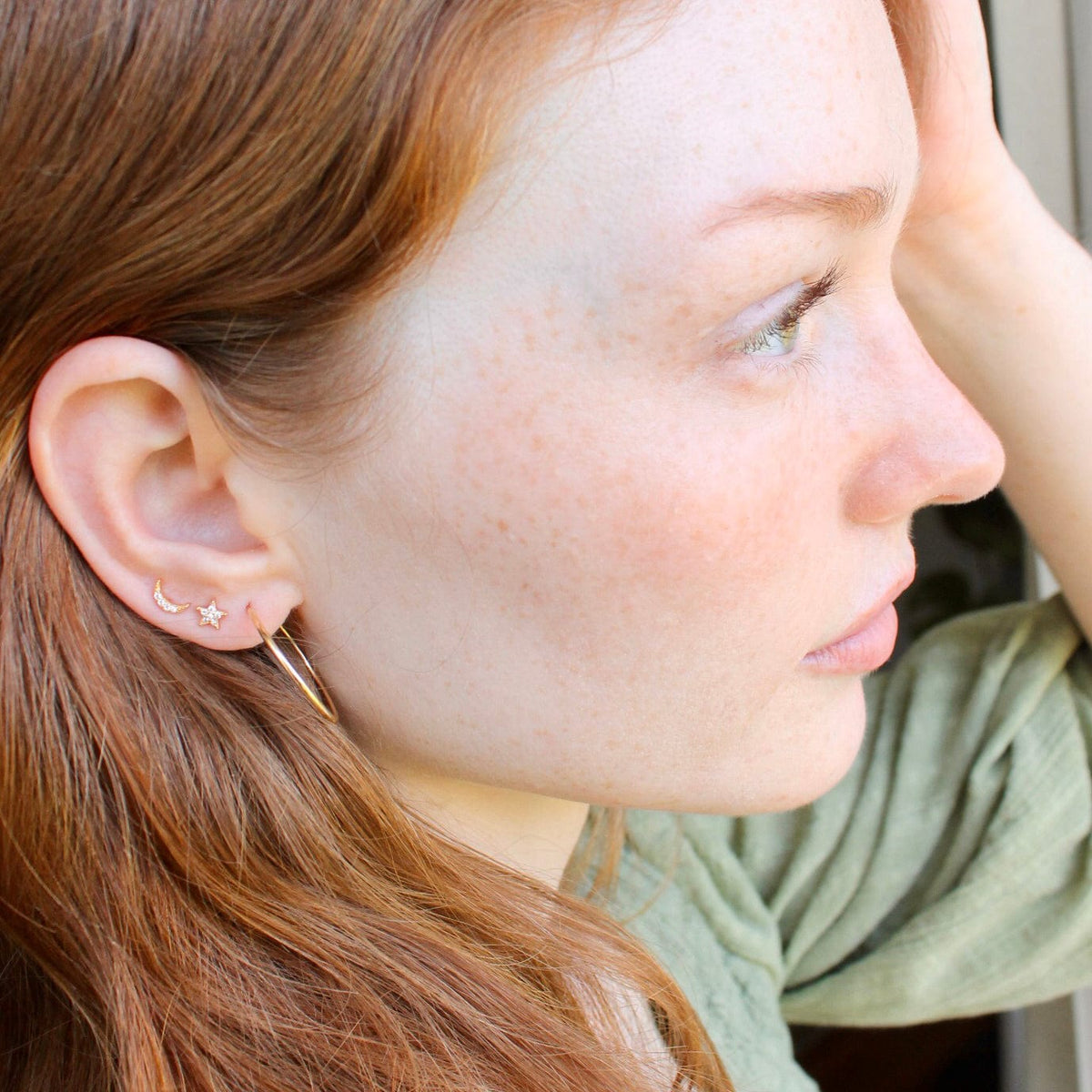 Woman with red hair looking away, wearing the Star and Moon Crystal Studs with the Star Crystal Stud