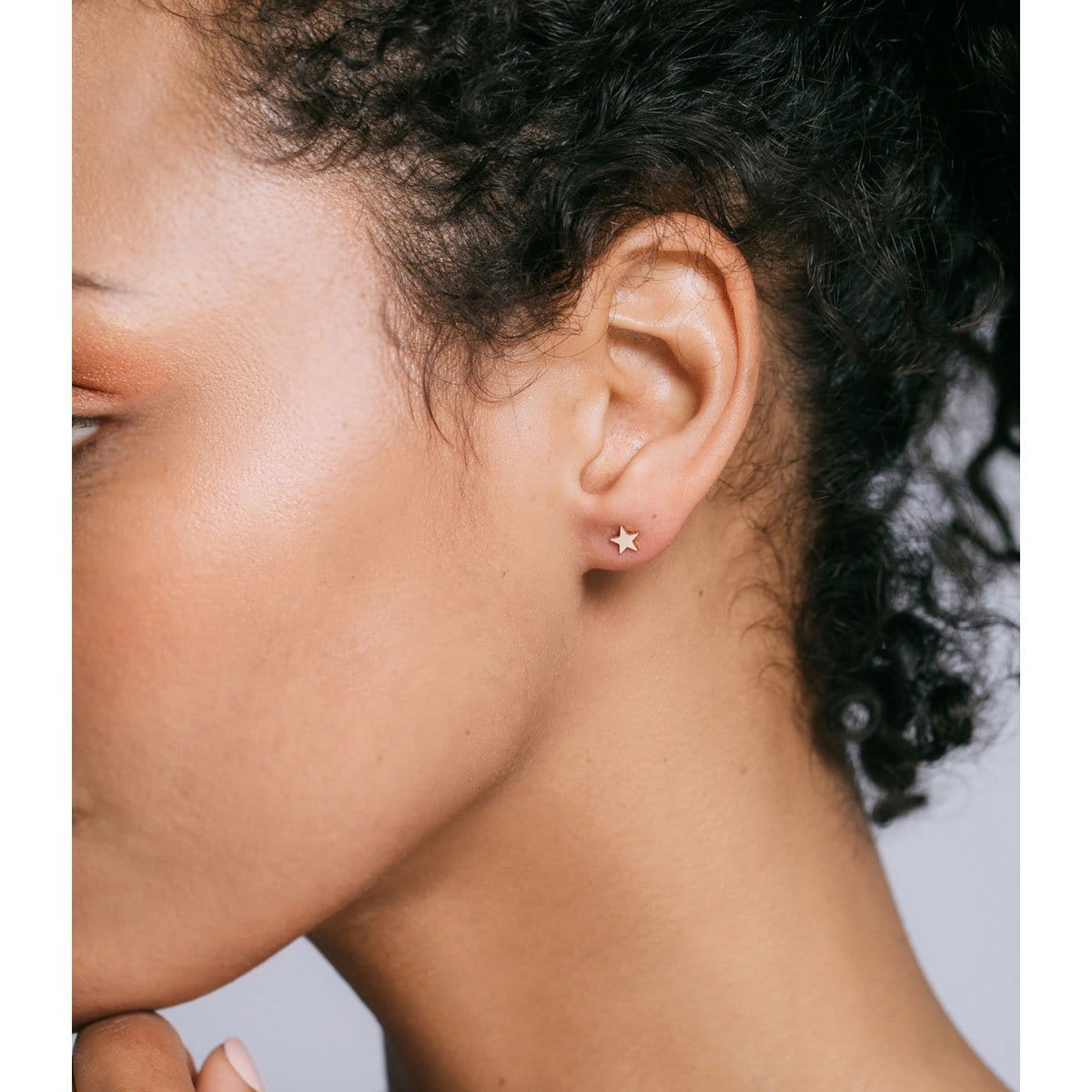 Woman with curly dark hair wearing a gold Star Stud