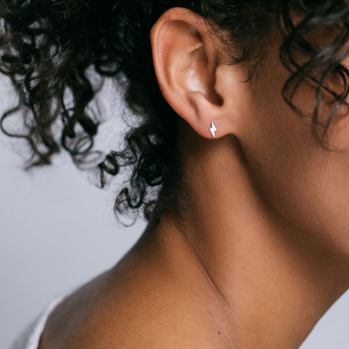 Woman with curly dark hair wearing a sterling silver Lightning Bolt Stud