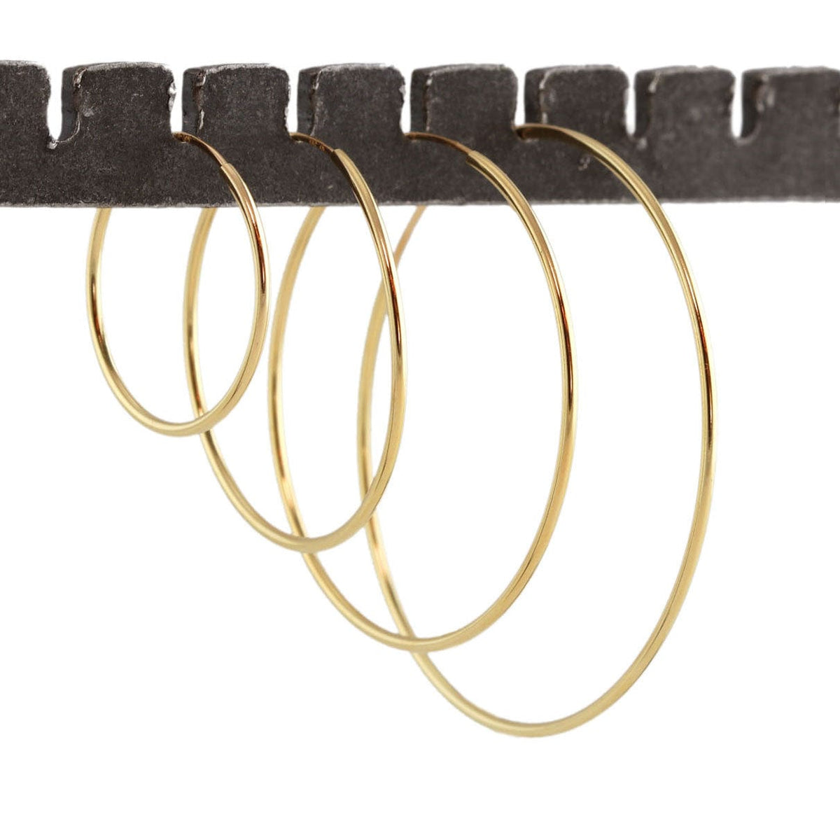 Gold-filled Featherweight Hoop Earrings in four sizes hanging from a bar