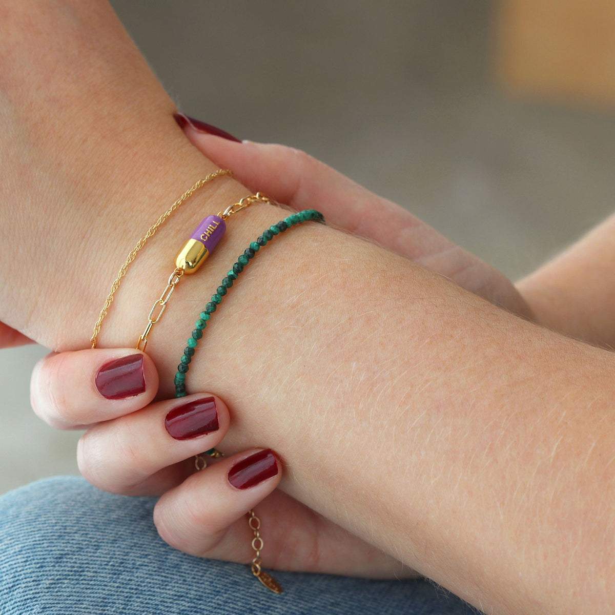 Wrist wearing an aubergine Chill Pill Bracelet with a green beaded bracelet