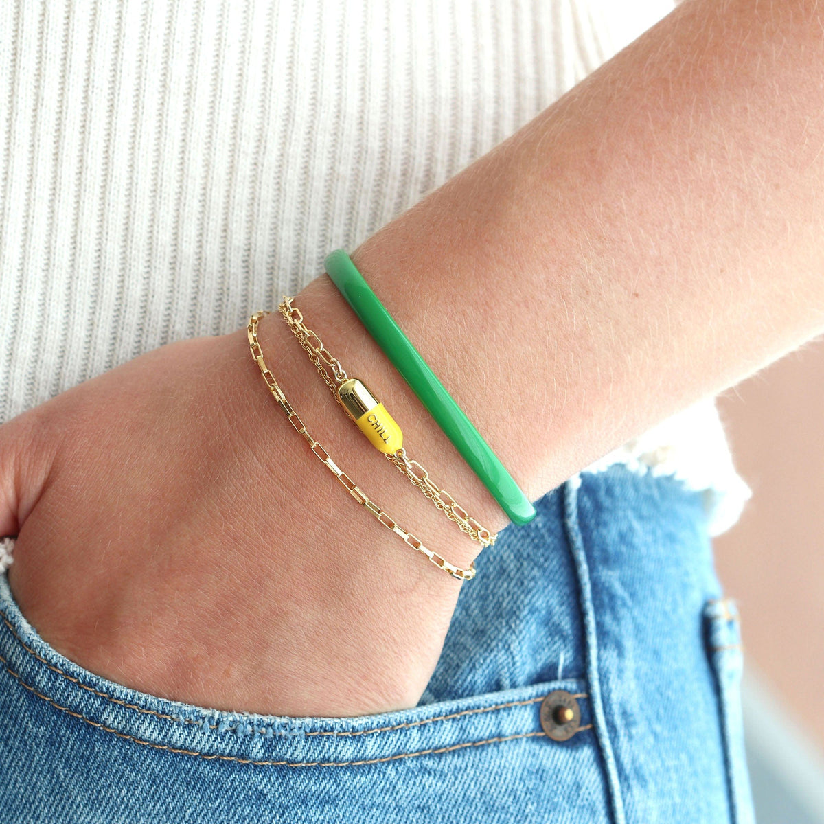 Wrist wearing a green Chill Pill Bracelet with a green enamel bangle