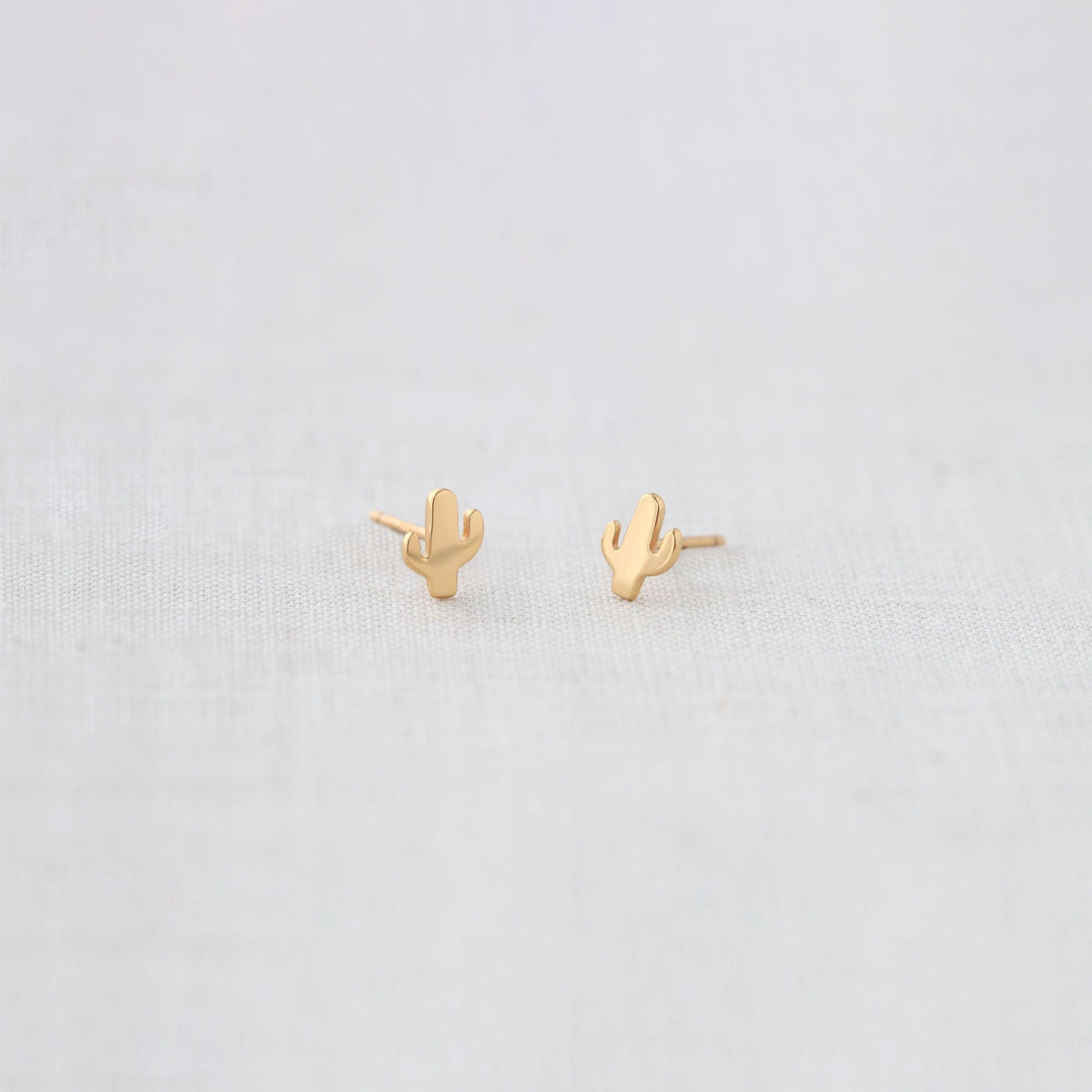 Gold Cactus Stud Earrings on white linen