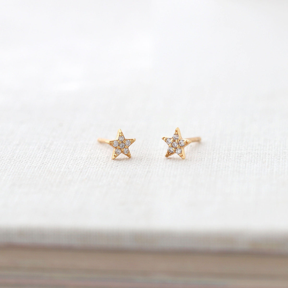 Star Crystal Stud Earrings in 18K gold vermeil on a white book