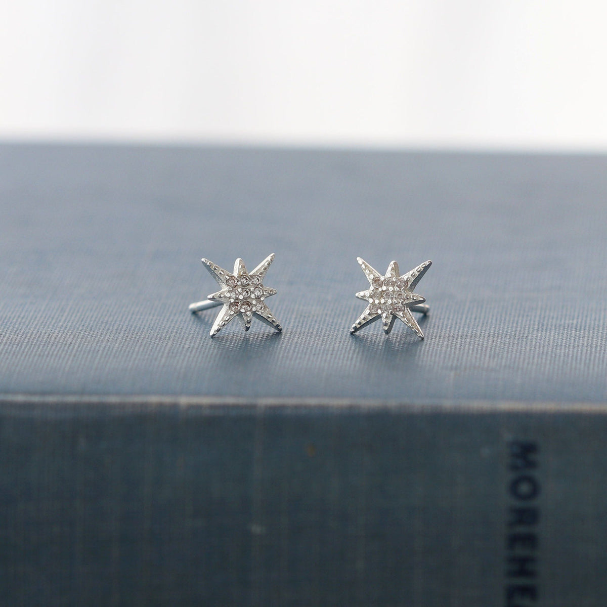 Starburst Crystal Stud Earrings in sterling silver on a dark book