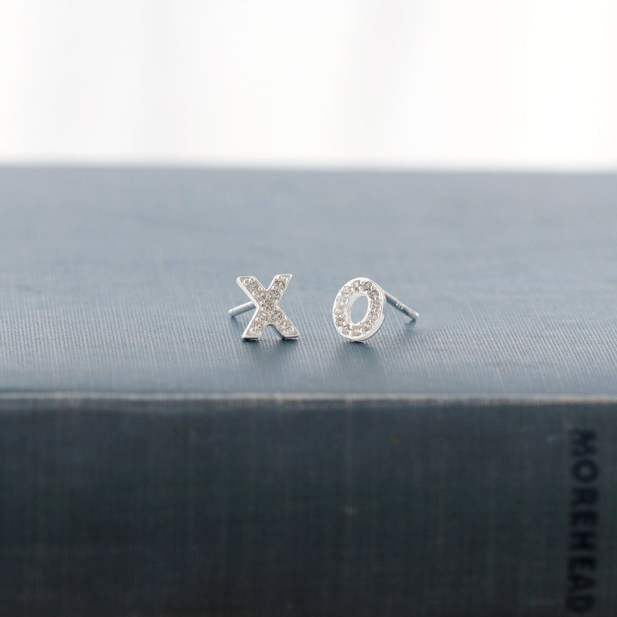 XO Crystal Stud Earrings in sterling silver on a dark book