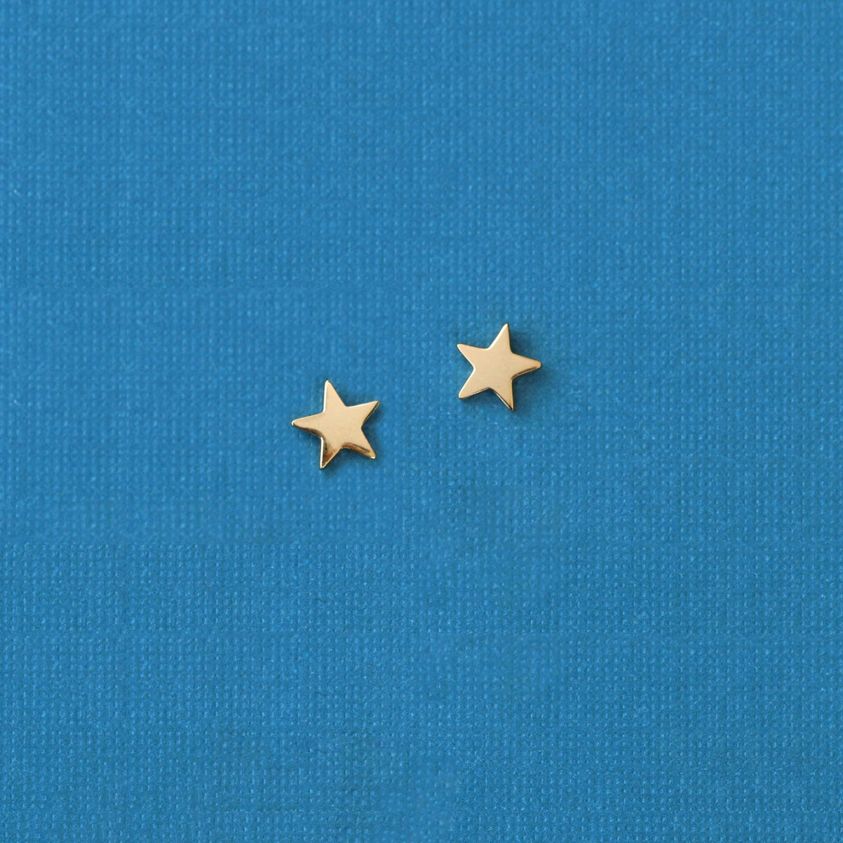 Gold Star Stud Earrings on blue fabric