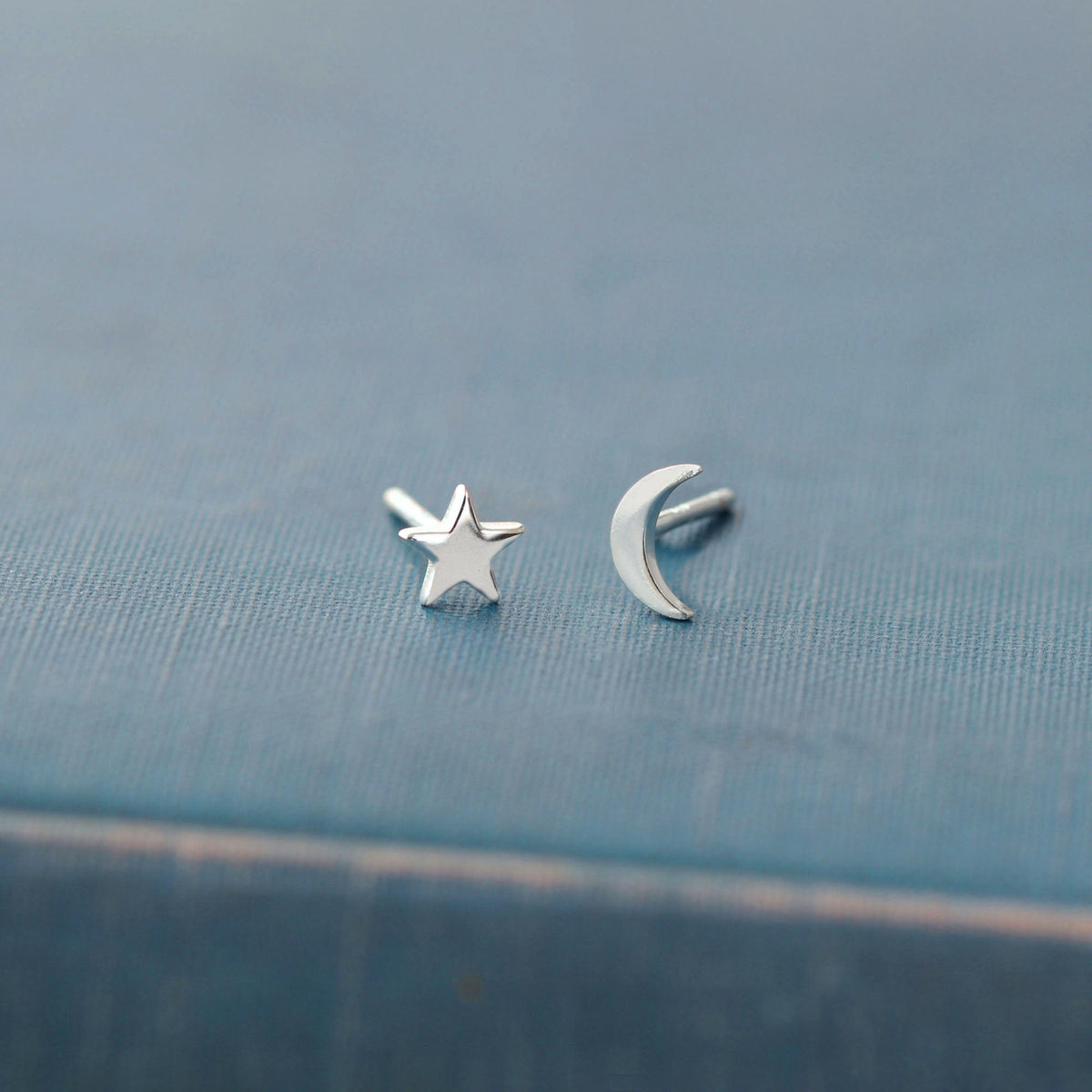 Star and Moon Stud Earrings in sterling silver on a blue book