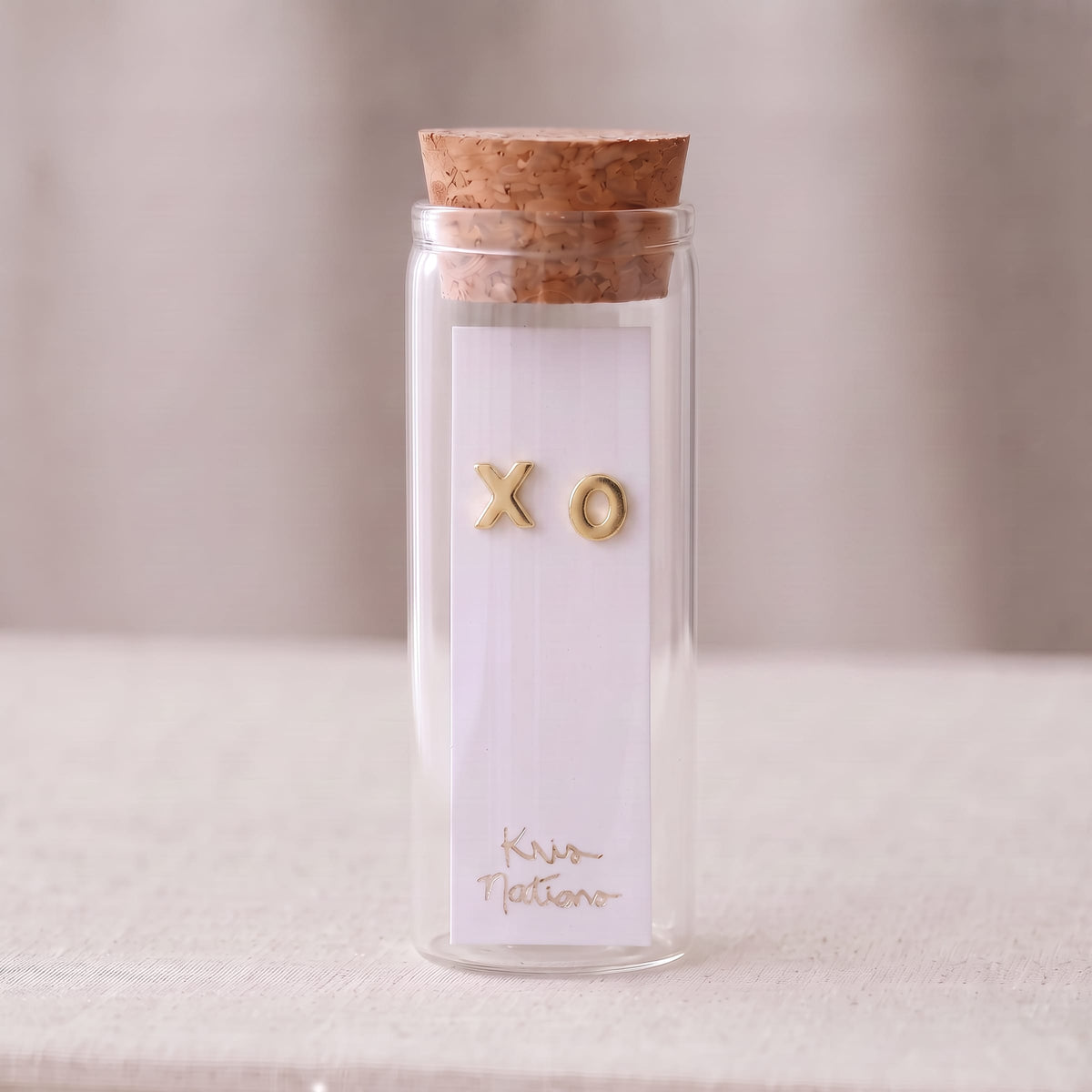 Gold XO Stud Earrings packaged in a small corked glass bottle