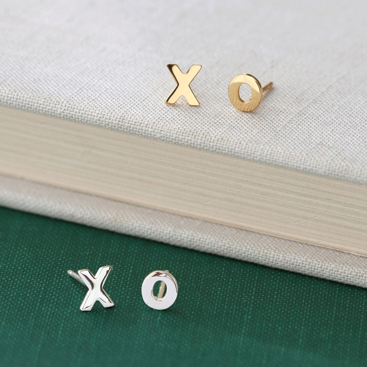 XO Stud Earrings in 18K gold vermeil and sterling silver on a book