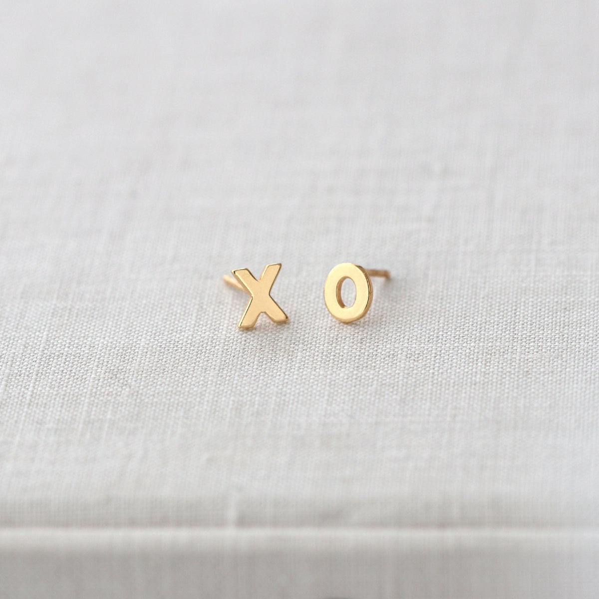 XO Stud Earrings in 18K gold vermeil on white linen