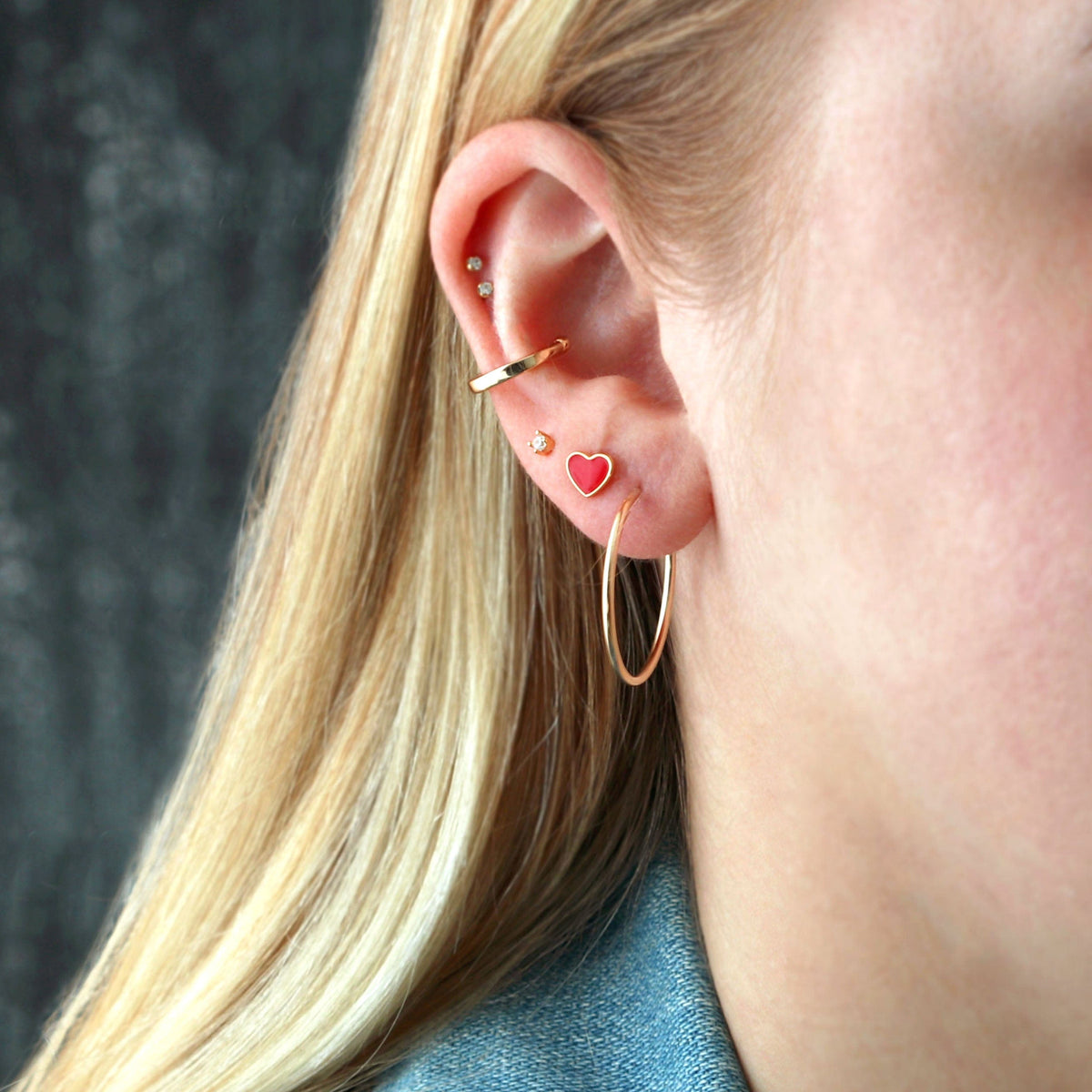 Featherweight Hoop worn in an ear stack with a red heart stud
