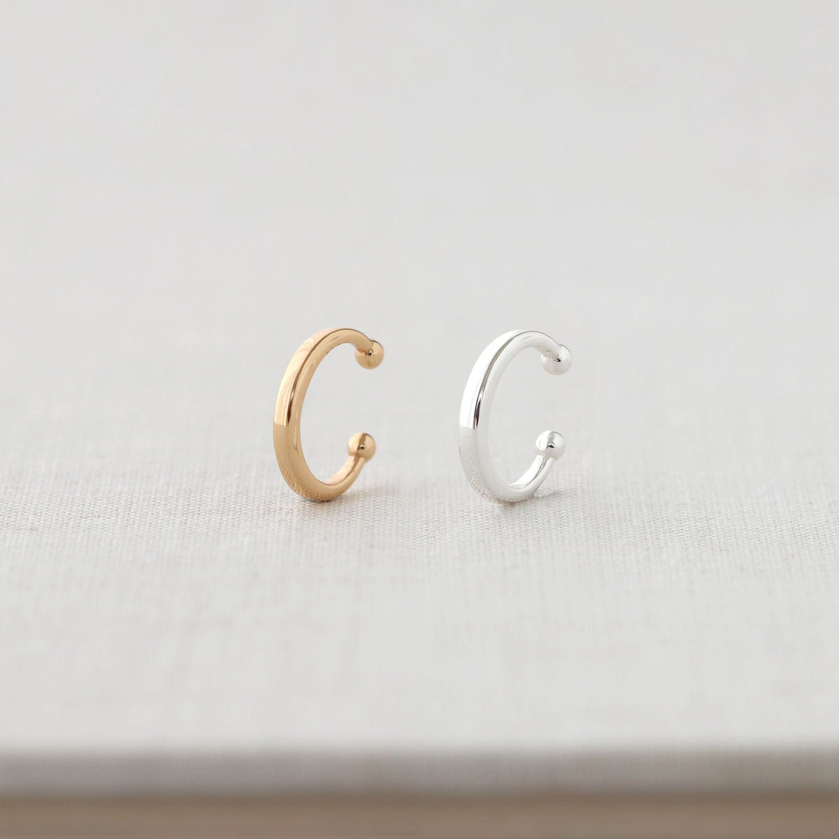 Round Ear Cuffs in 18K gold vermeil and sterling silver on white linen