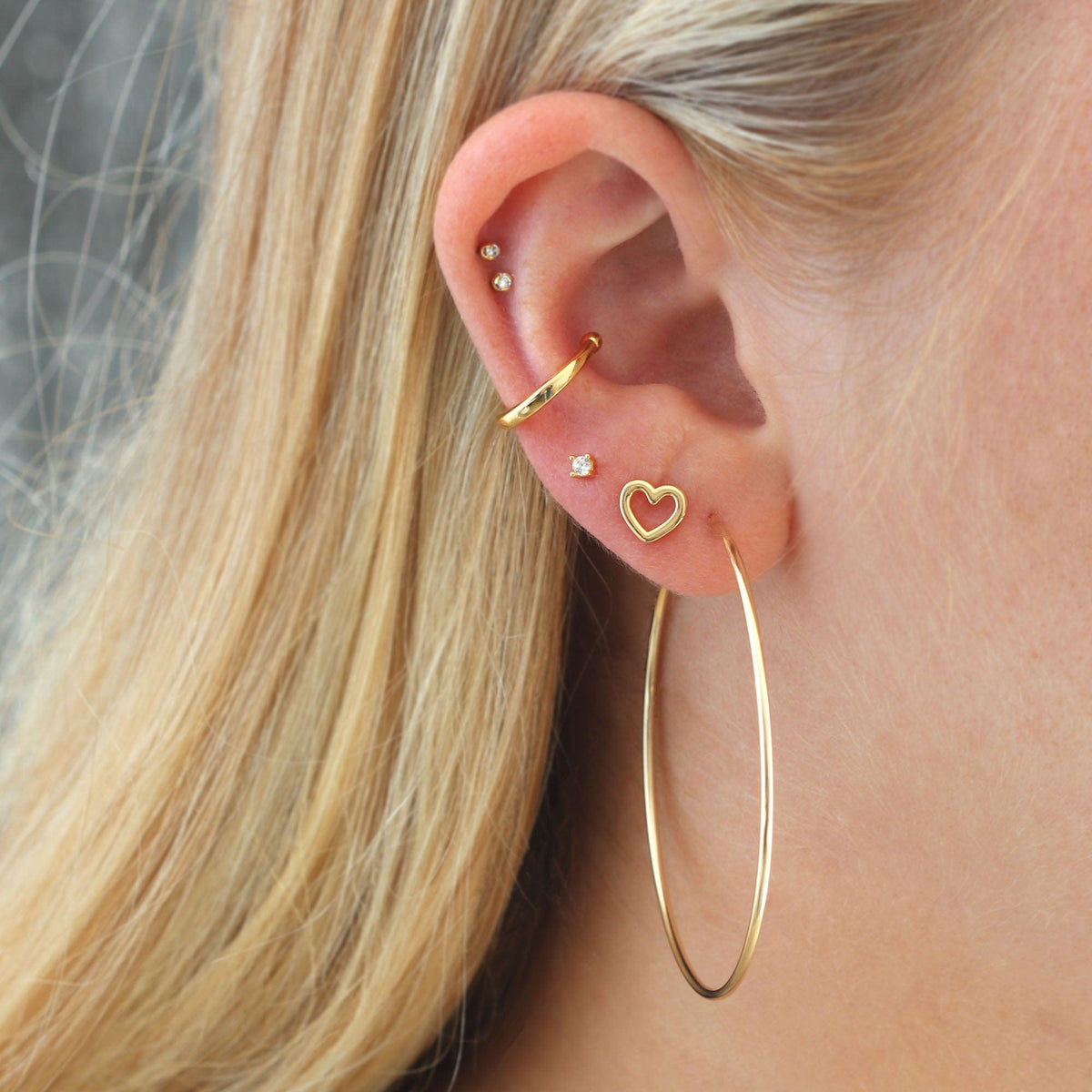 Large Featherweight Hoop worn in an ear stack with an open heart stud and an ear cuff