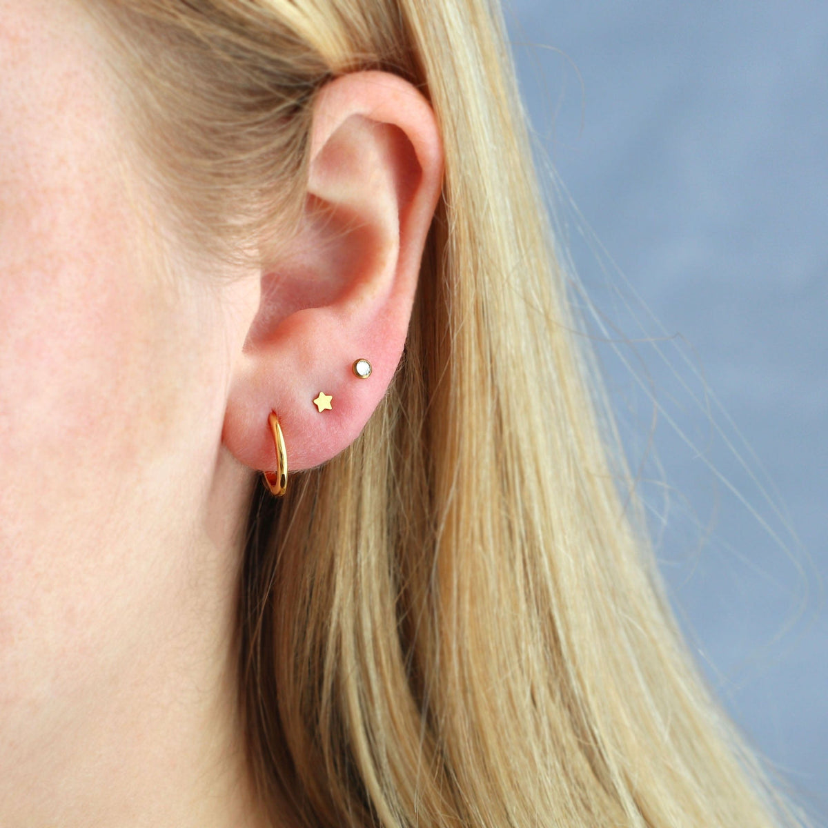 Gold Classic 12mm Hinged Huggie Hoop worn in an ear stack with small studs