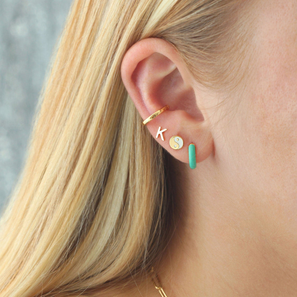 Green Enamel Huggie Hoop worn in an ear stack with gold studs
