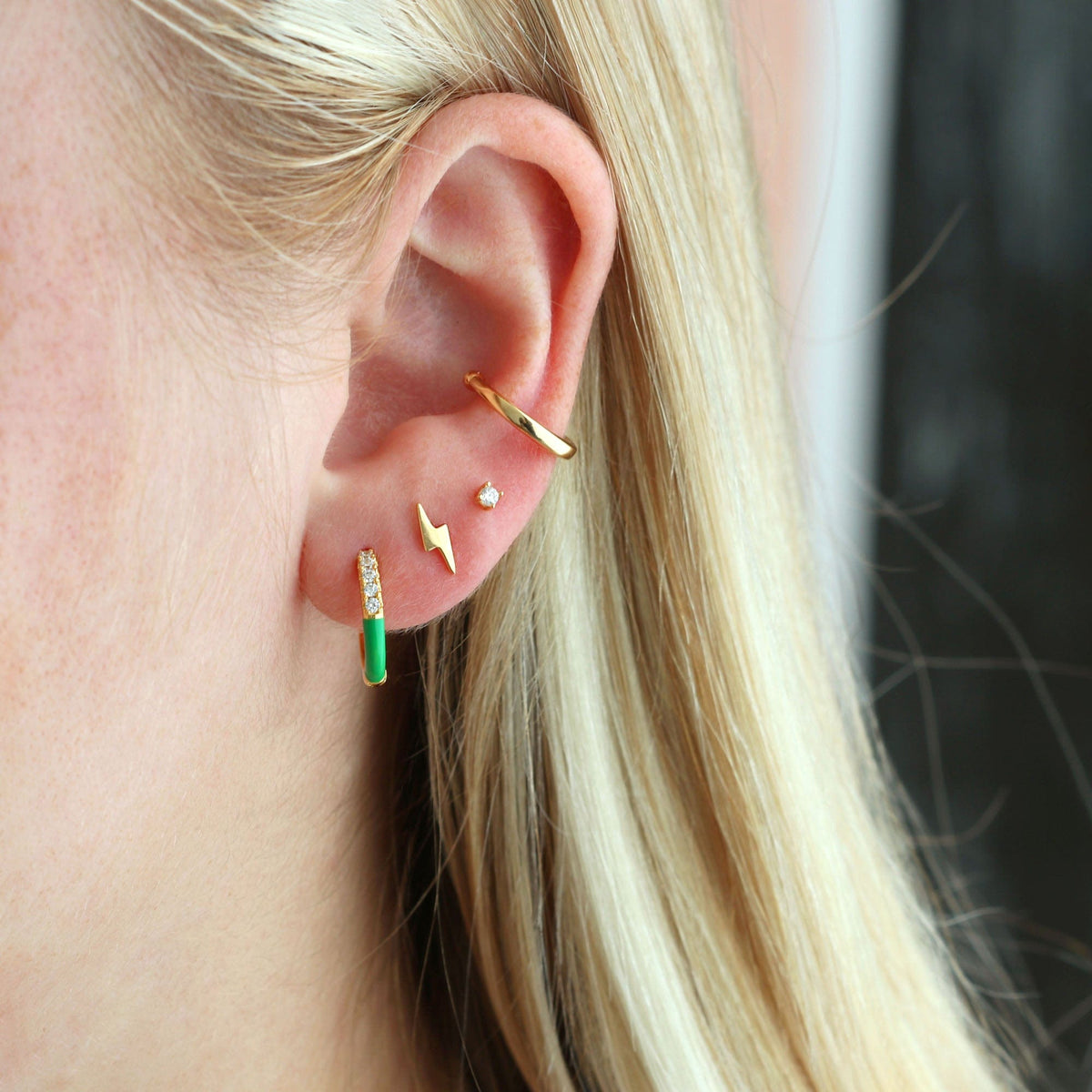 Gold Lightning Bolt Stud worn in an ear stack with a green enamel huggie and an ear cuff
