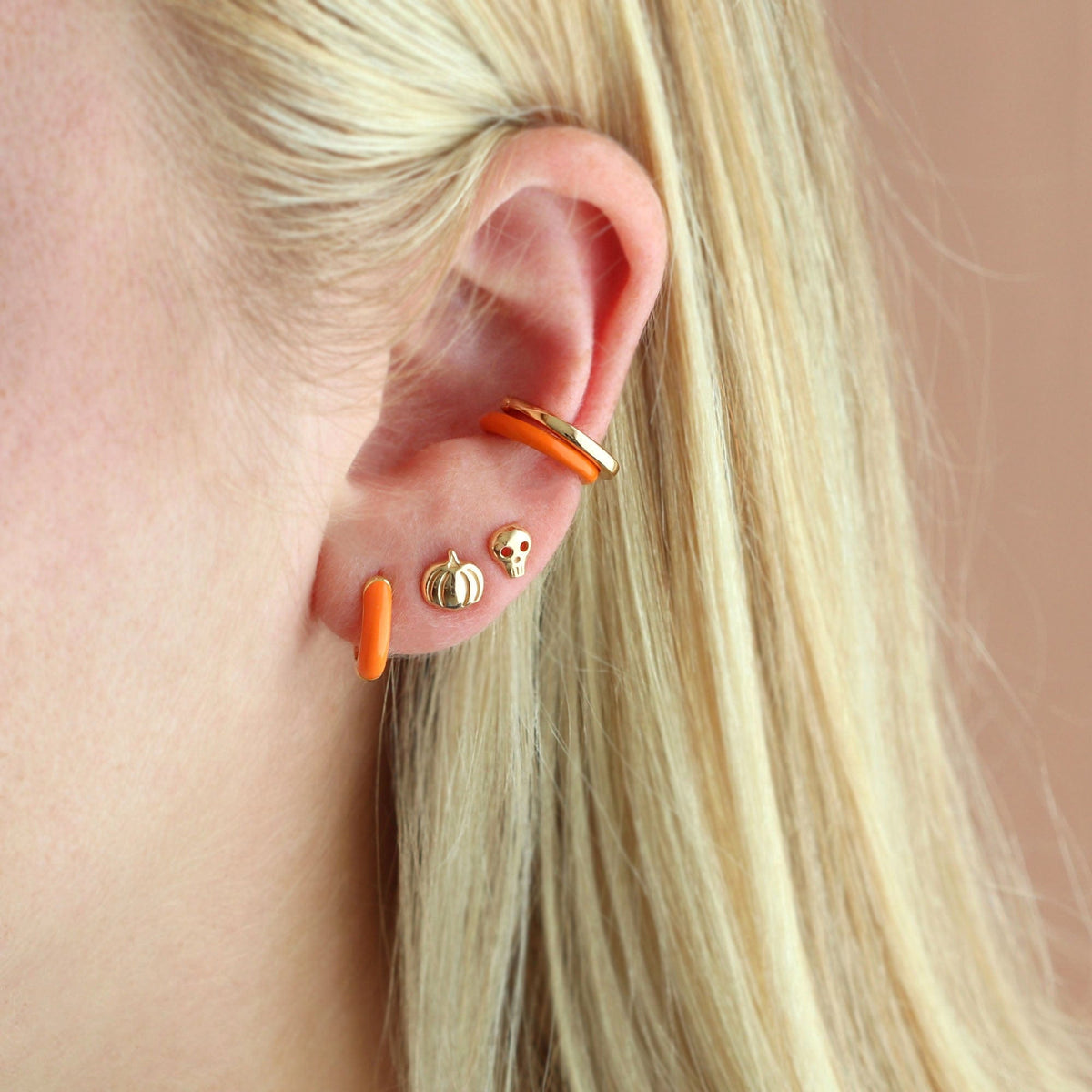 Orange Enamel Huggie Hoop worn in an ear stack with gold studs