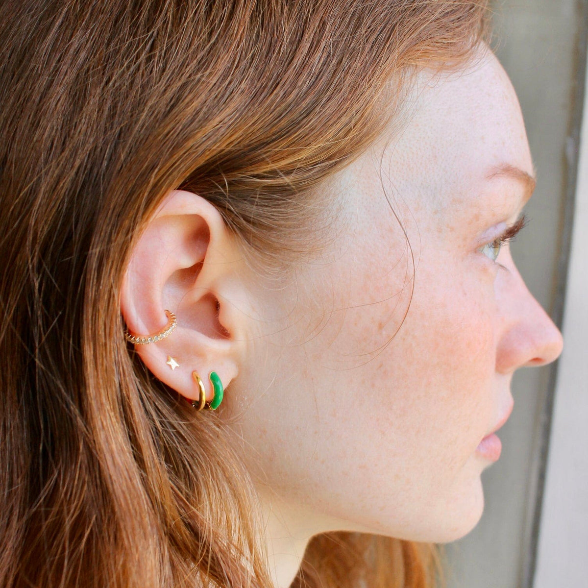 Woman with red hair wearing a green Enamel Huggie Hoop