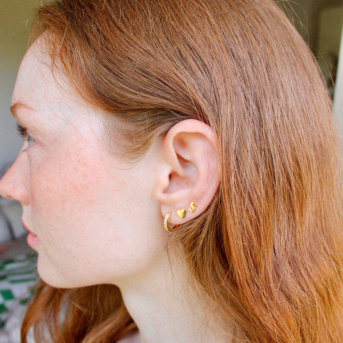 Woman with red hair wearing gold Single Letter Studs