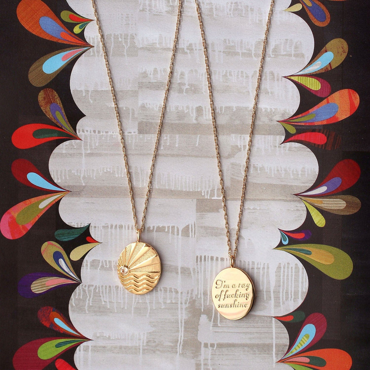 Gold Ray of Sunshine pendants front and back on a colorful swirled background