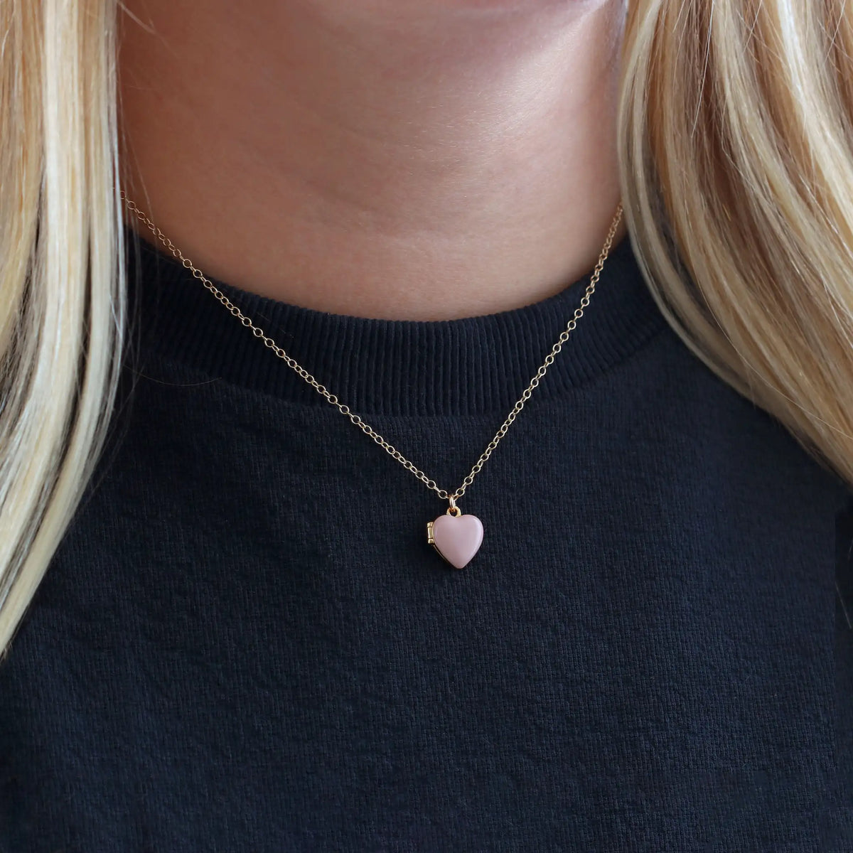 Woman with blonde hair in a black top wearing a pink Enamel Heart Locket