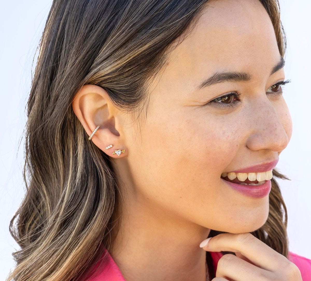 Smiling woman with long brown hair wearing a gold Bar Dash Crystal Stud and ear cuff