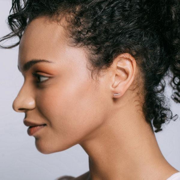 Profile of a woman with curly dark hair wearing a gold Bar Dash Stud