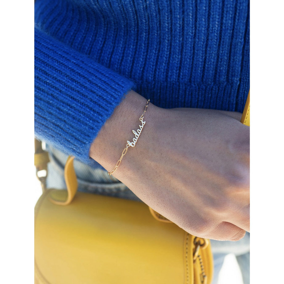 Wrist in a blue sweater wearing the gold Badass Bracelet