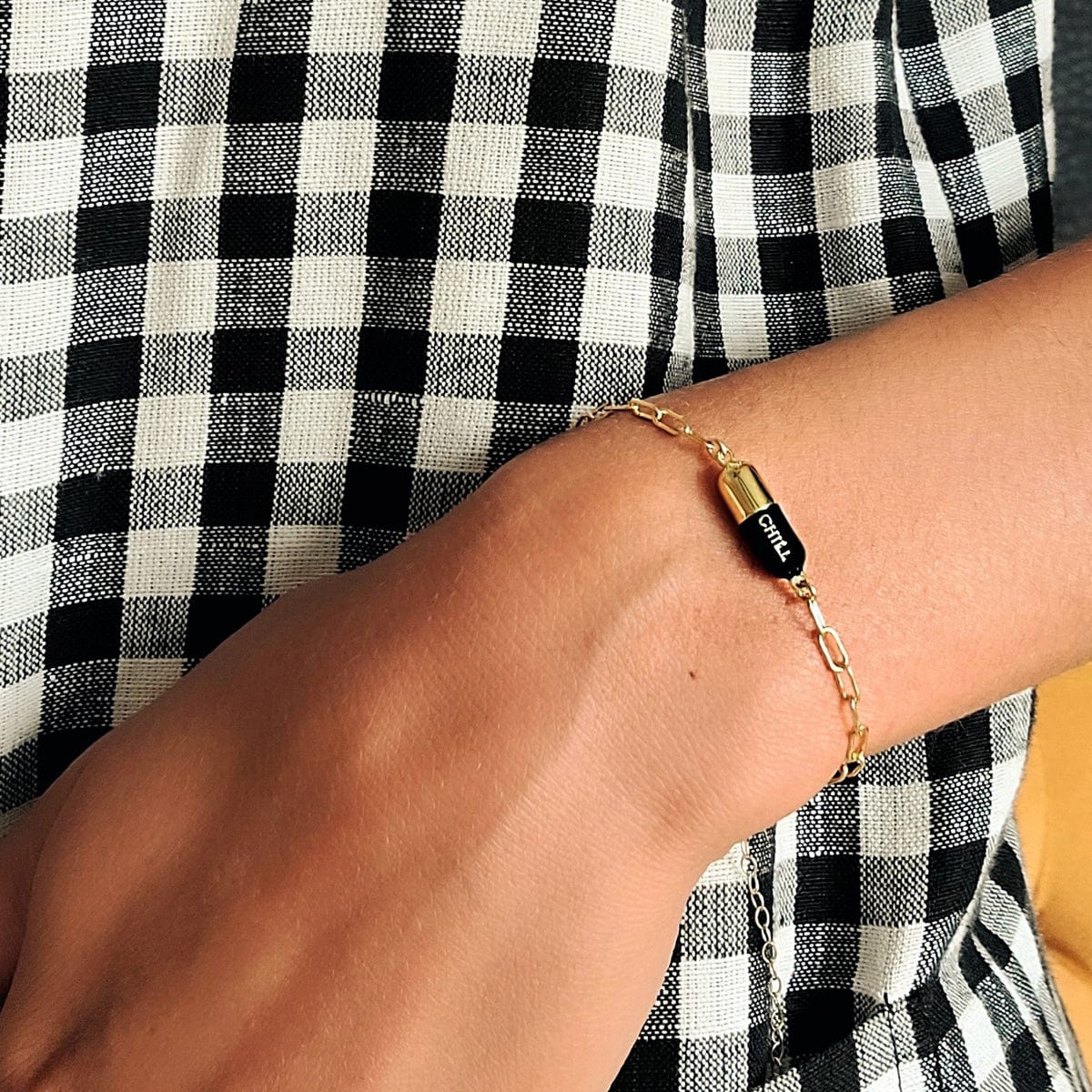 Wrist against gingham wearing a black Chill Pill Bracelet