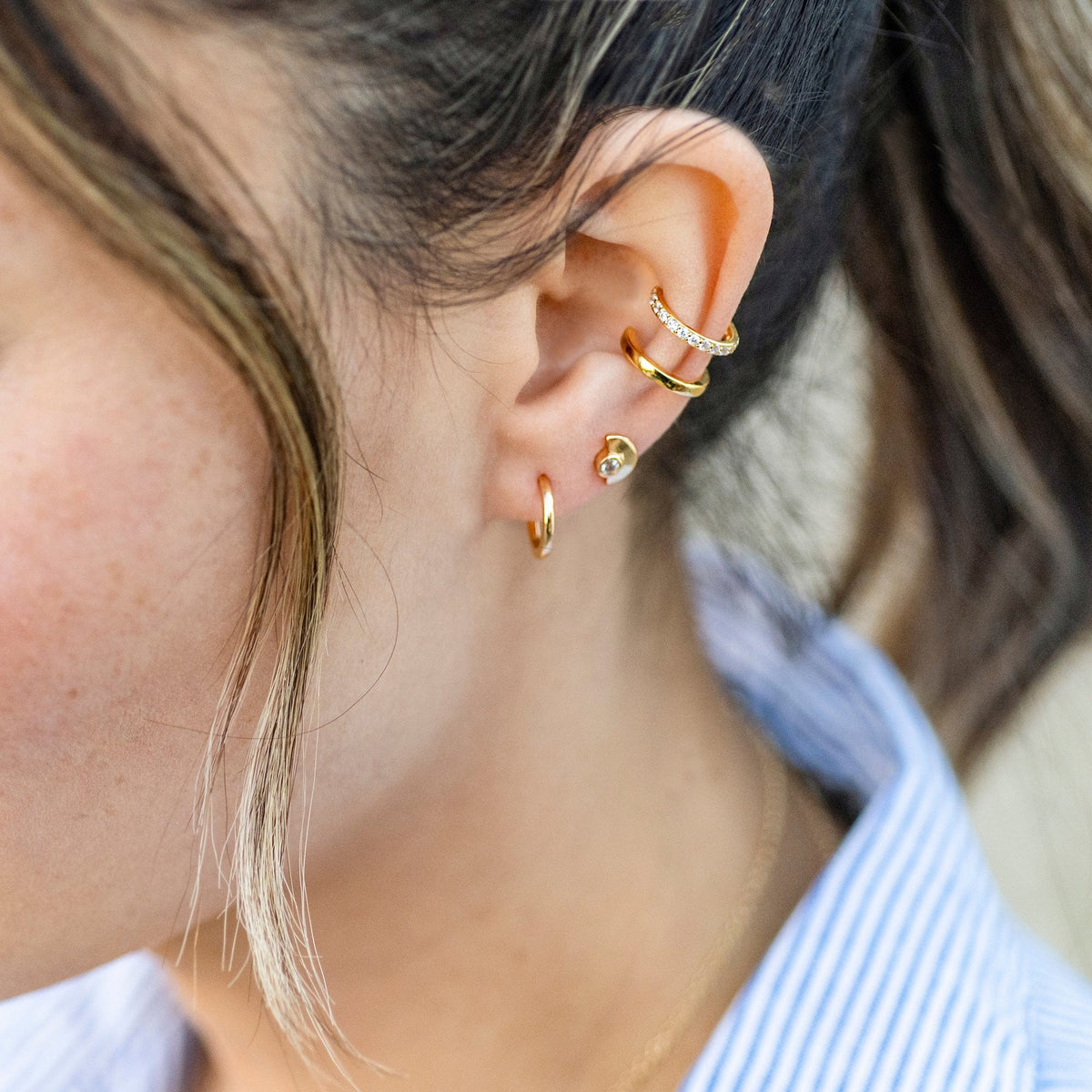 Gold Classic 12mm Hinged Huggie Hoop worn in an ear stack with ear cuffs