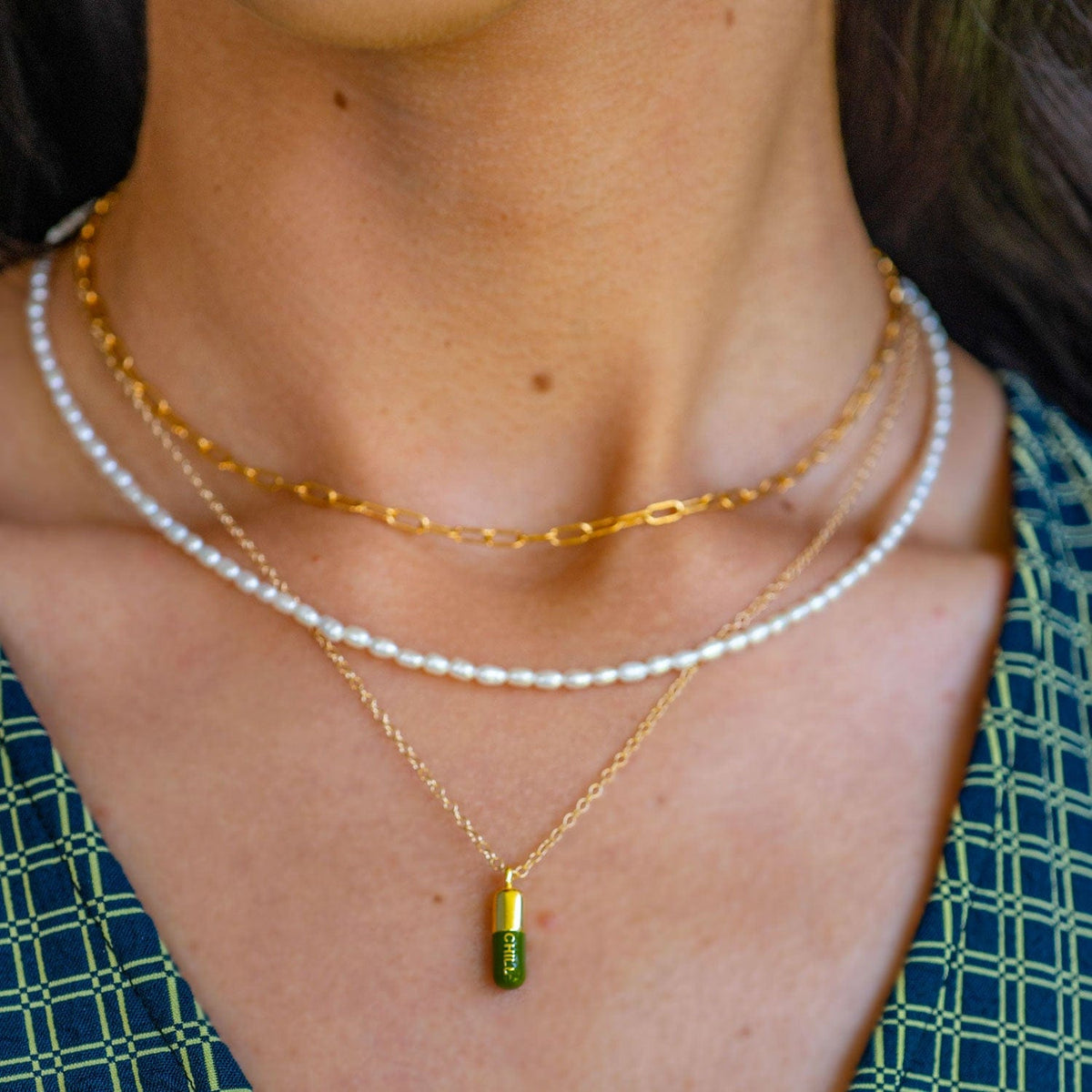 Green Chill Pill necklace layered with a pearl strand and a gold chain