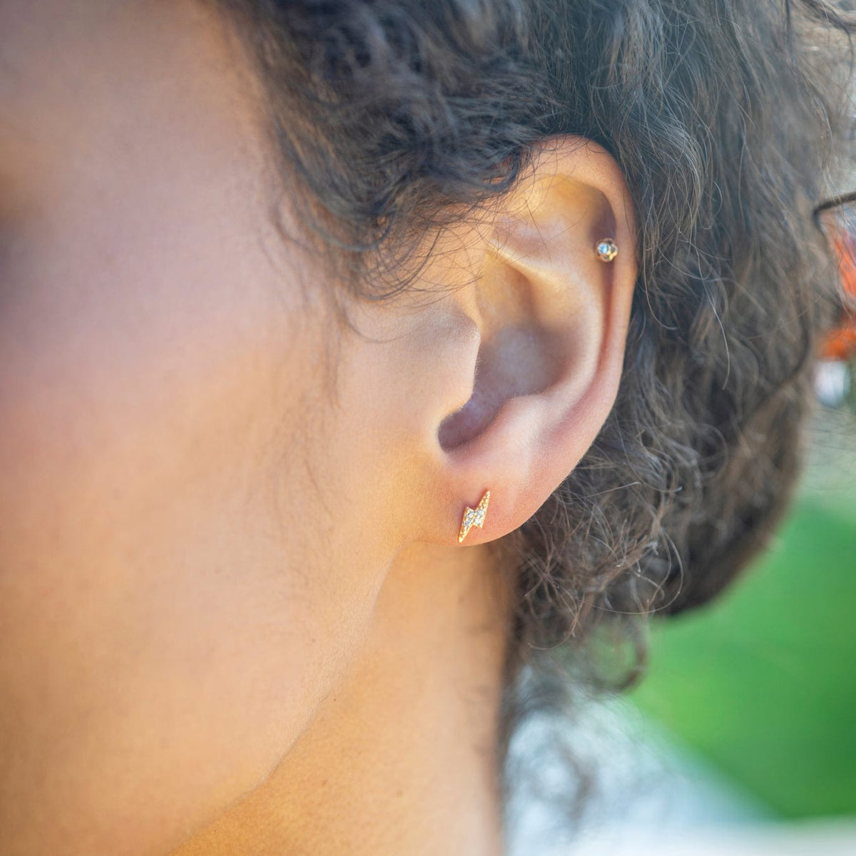 Close-up of an ear wearing a gold Lightning Bolt Crystal Stud