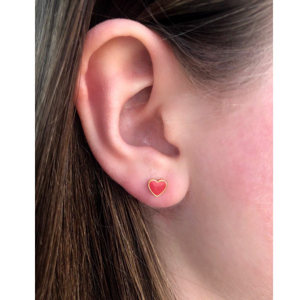 Close-up of an ear wearing a red Petite Heart Enamel Stud